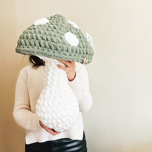 green mushroom pillow hold by a person
